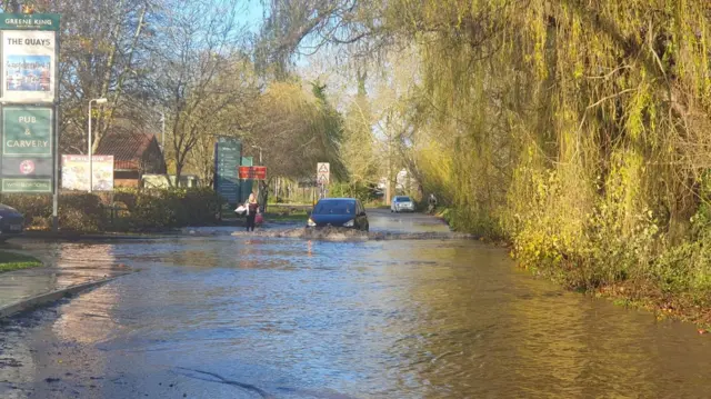 A black car driving in floodwater in Northampton.