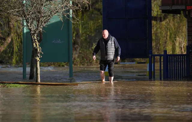 A man walks through floodwater near the Billing Aquadrome in Northamptonshire.