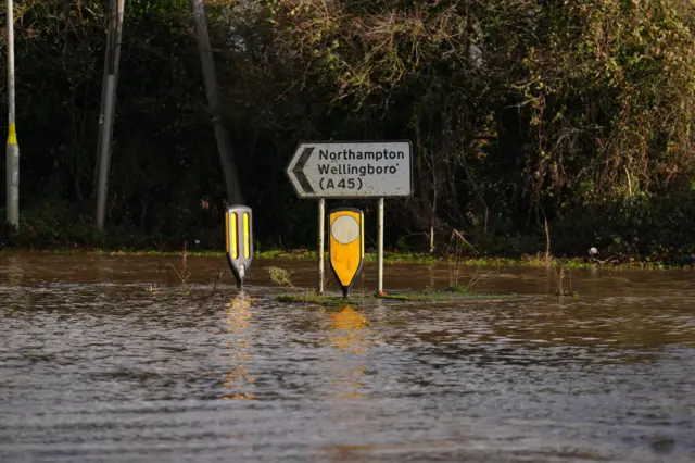 A sign for the A45 road to Northampton and Wellingborough in the midst of high flood water