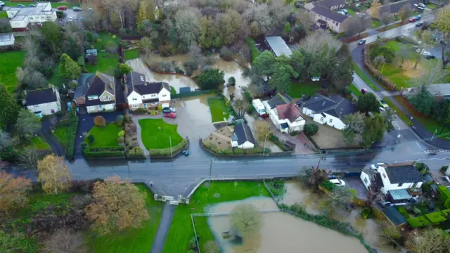 Large houses flooded either side of a road.