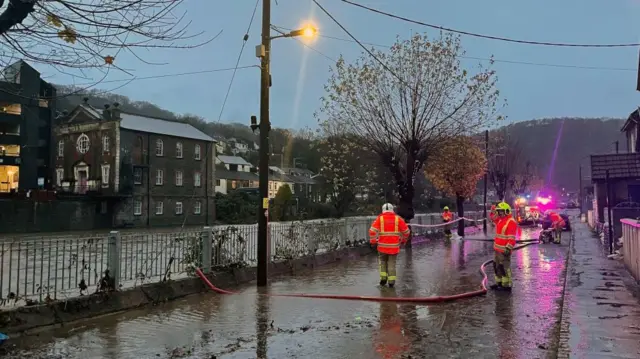 Firefighters pumping flood waters from a flooded road in Pontypridd, Wales