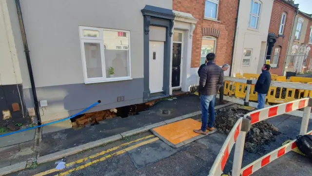 A possible sinkhole in Northampton, there are two men standing outside a home and barriers have been put up