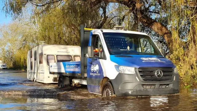 Truck with a caravan driving in flooded water