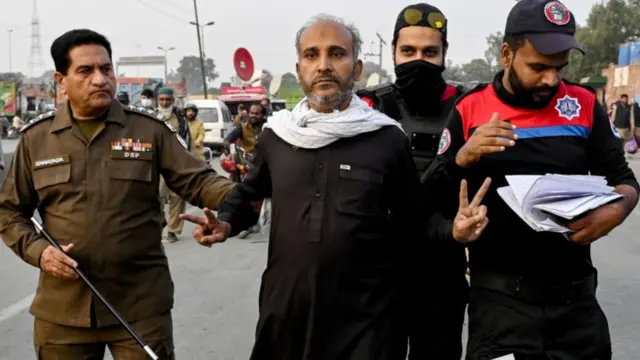 Security personnel detain a Khan supporter during a rally in Lahore on Sunday