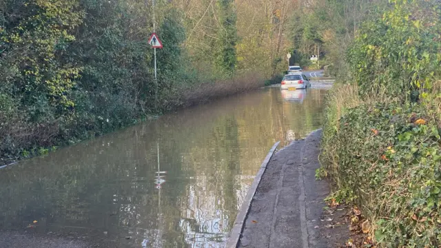 Cars trying to pass through Down Road in Winterbourne which is flooded