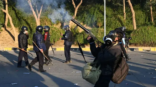 Policemen fire tear gas shells to disperse PTI supporters.