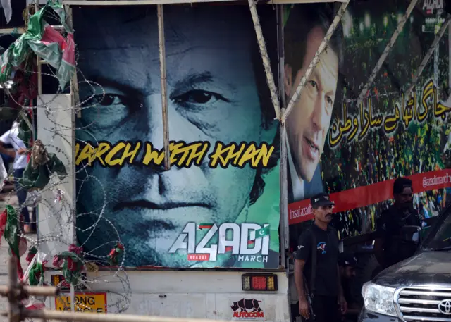 Pakistani police commandos stand guard beside images of opposition politician Imran Khan at a protest site in front of the Parliament building in Islamabad on August 20, 2014.