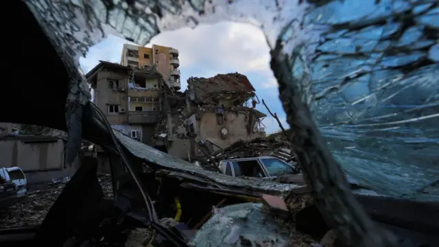 A damaged building is pictured through the wreckage of a vehicle, in the aftermath of Israeli strikes on Beirut's southern suburbs, amid the ongoing hostilities between Hezbollah and Israeli forces