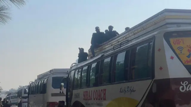 A coach with some men sitting on its roof