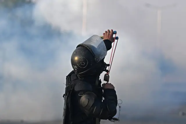 A policeman pelts stones to disperse supporters of Pakistan Tehreek-e-Insaf (PTI) party during a protest to demand the release of former prime minister Imran Khan, in Islamabad on November 26, 2024.