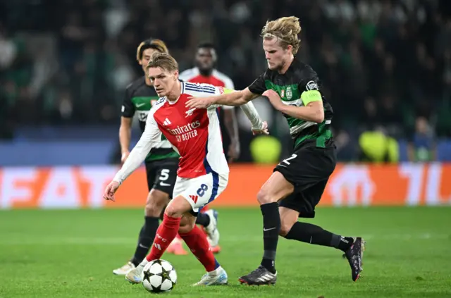 Martin Odegaard of Arsenal runs with the ball whilst under pressure from Morten Hjulmand of Sporting CP