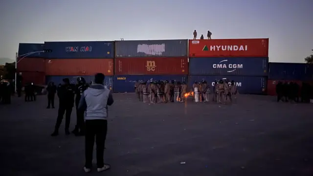 Group of officers standing next to a wall of shipping containers