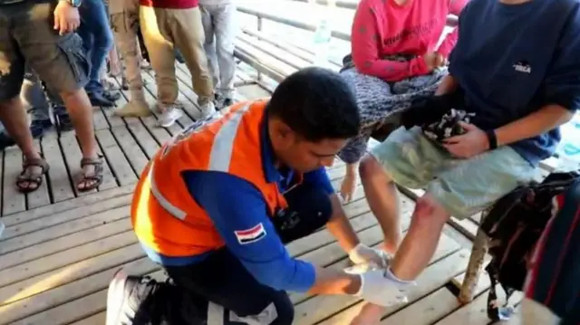 A person in a hi vis tending to a wound on someone's leg