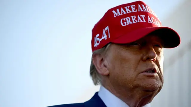 Donald Trump wears a red "Make America Great Again" cap