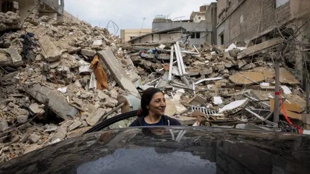 A woman stands outside her destroyed house, after a ceasefire between Israel and Iran-backed group Hezbollah took effect at 0200 GMT on Wednesday