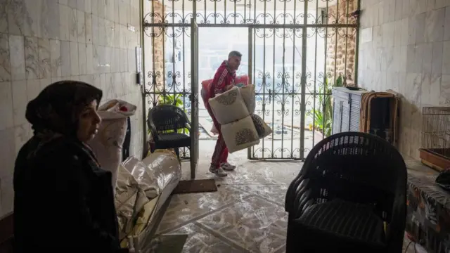 Ibrahim Khater, 51, carries mattresses back into his destroyed house, after a ceasefire between Israel and Iran-backed group Hezbollah took effect at 0200 GMT on Wednesday