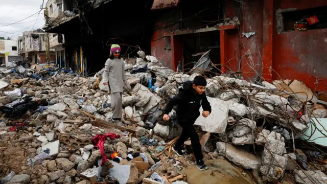 Hashim Fakih, 10, and Fatima Fakih, 11, walk in front of their destroyed house, after a ceasefire between Israel and Iran-backed group Hezbollah took effect at 0200 GMT on Wednesday