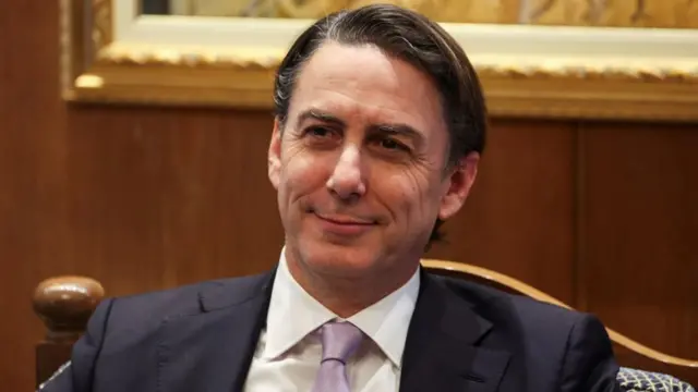 US special envoy Amos Hochstein smiles as he sits in an armchair, hair slicked back and wearing a suit and light purple tie.