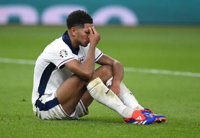 Jude Bellingham sits on the field dejected after England's Euros final loss