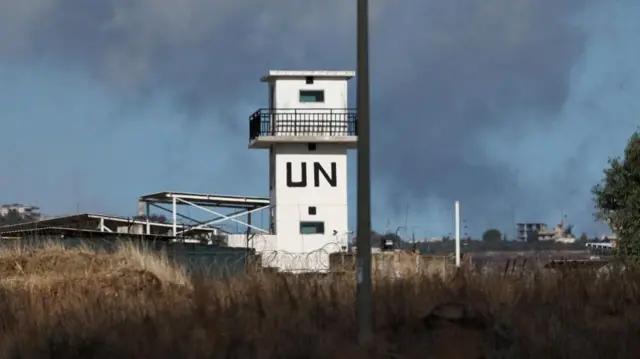 An empty white observation tower that has UN on its side in big black letters