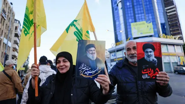 People carry Hezbollah flags and posters with images of late Hezbollah leader Sayyed Hassan Nasrallah, at the entrance of Beirut's southern suburbs, after a ceasefire between Israel and Iran-backed group Hezbollah took effect at 0200 GMT on Wednesday after U.S. President Joe Biden said both sides accepted an agreement brokered by the United States and France, in Lebanon, November 27, 2024