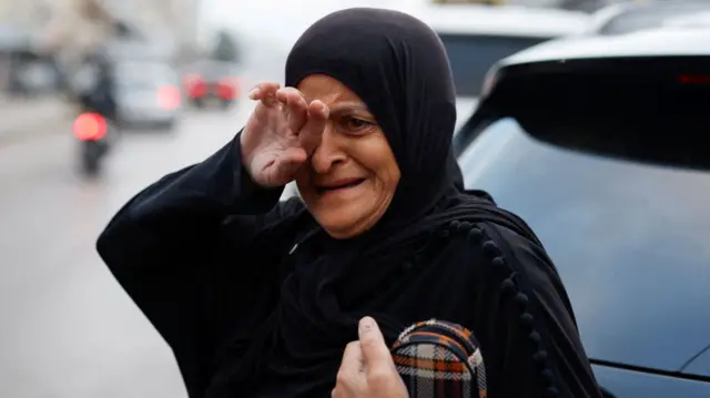 A woman covering her eye with one hand while clutching a purse