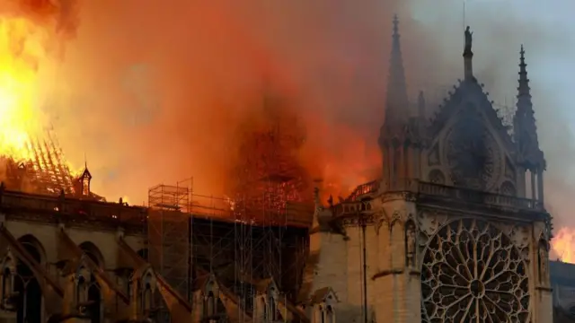 A cloud of smoke and flame eats into the side of the gothic cathedral