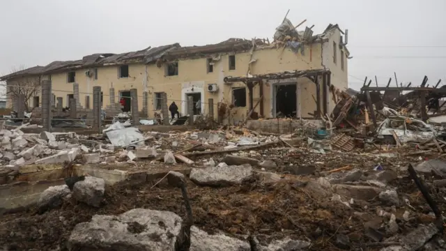 Residents stand next to their house damaged by a Russian missile strike, amid Russia's attack on Ukraine, on the outskirts of Odesa