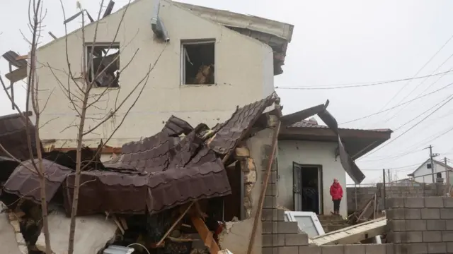 A girl stands next to her house damaged by a Russian missile strike