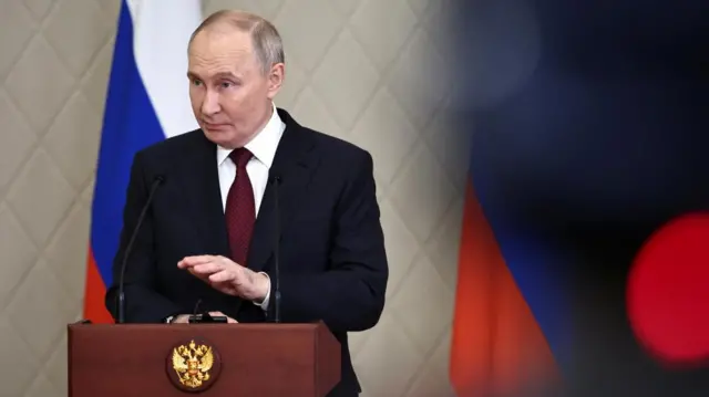 Russian President Vladimir Putin stands behind a lectern