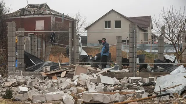 Residents stand next to their houses damaged by a Russian missile strike, amid Russia's attack on Ukraine, on the outskirts of Odesa