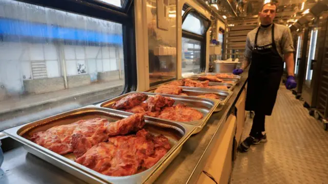 A staff member aboard a train preparing turkey dishes