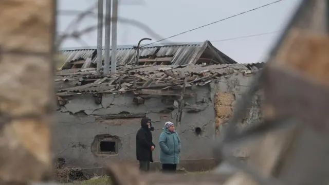 Residents look on next to a building damaged by a Russian missile strike, amid Russia's attack on Ukraine, on the outskirts of Odesa