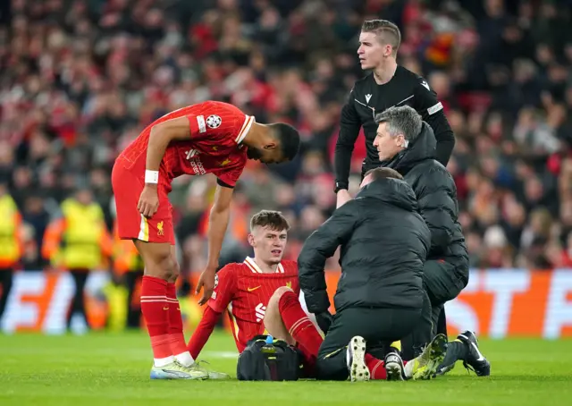 Liverpool's Conor Bradley sits on the pitch as he receives treatment for an injury during the UEFA Champions League, league stage match at Anfield