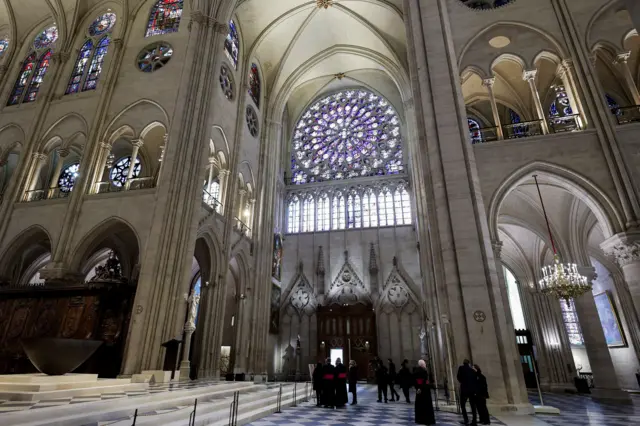 Rose window. It is a bright, circular window made up of many panes of purple and blue glass, high up in the cathedral.