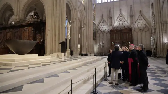 Macron and others are in the Notre-Dame cathedral as a group looking at the statues as they are