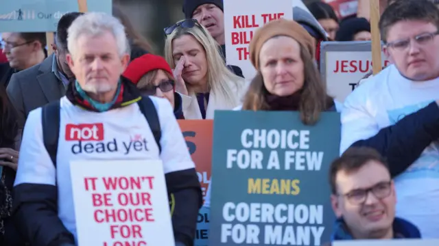 Demonstrators look disappointed, as they hold posters objecting to the bill