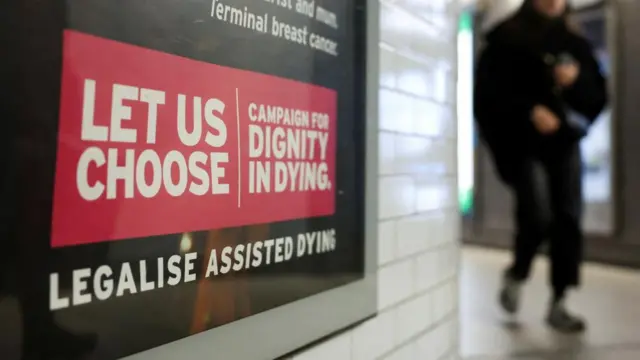 A tube passenger walks past an assisted-dying rights billboard