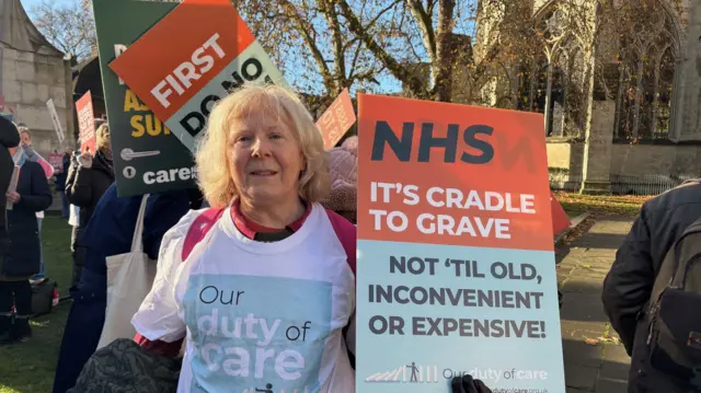 Julie holds a placard outside parliament