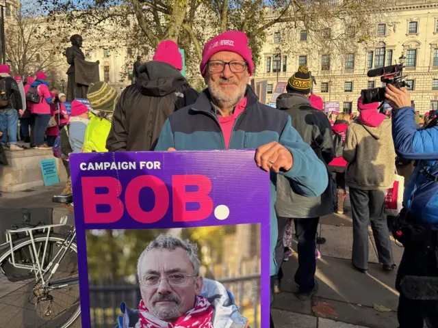 Mick outside Westminster with a poster of Bob