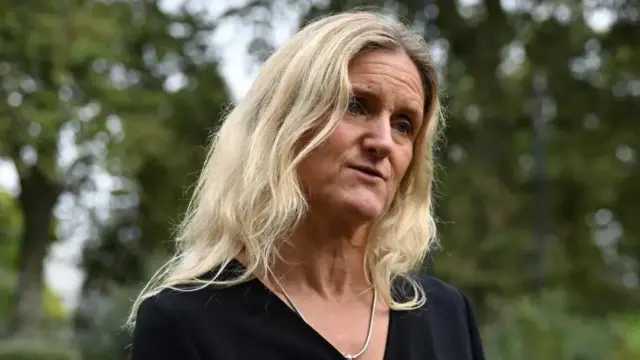 Kim Leadbeater speaking with her head tilted to one side, wearing a v-neck black top and a silver necklace