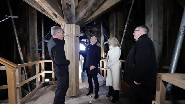 Macron is standing in the spire of Notre-Dame with three others as they are explaining the restoration to himaining