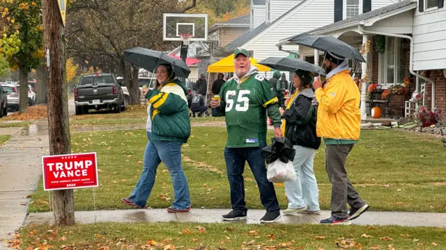 Green Bay supporters holding umbrellas in a suburban street