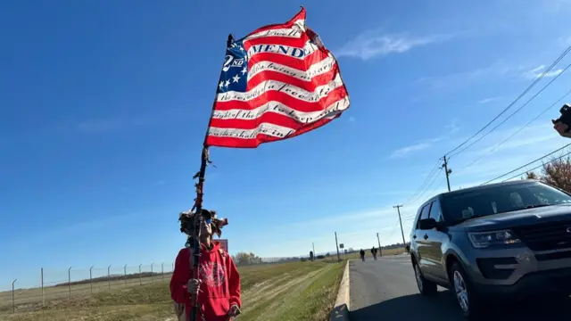 A man, holding a stars-and-stripes flags, before he goes in to the rally