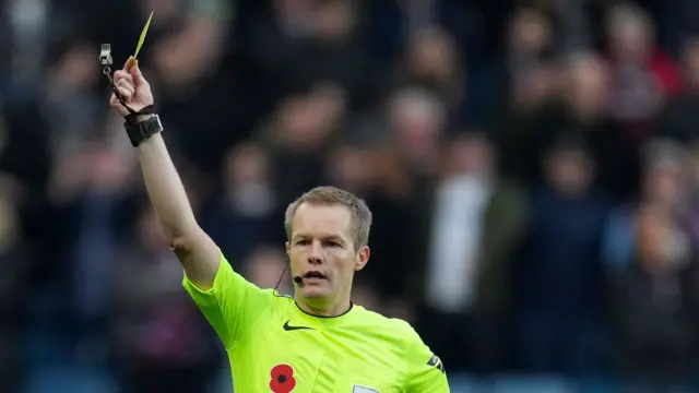 Referee Gavin Ward shows the yellow card