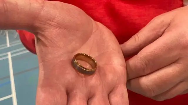 A hand with a gold ring in its palm.