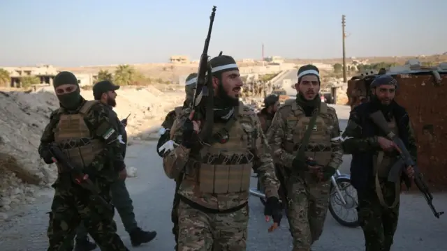 Opposition fighters patrol the streets after they took control of the city of Maarat al-Numan where the international road M5 passes through