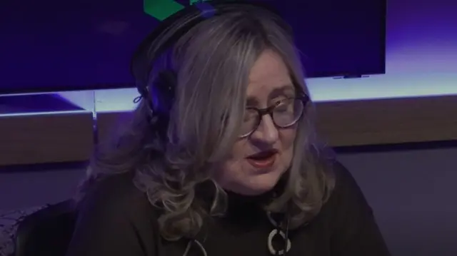 Margret O'Callaghan wearing a dark green top, she has headphones on her head