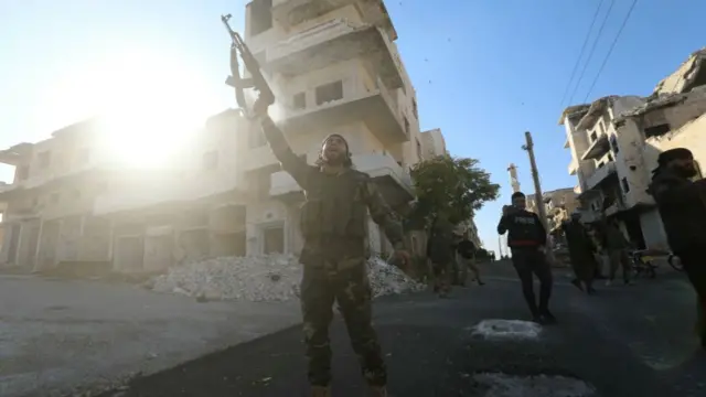 Anti-government fighters celebrate in a street in Maaret al-Numan in Syria's northwestern Idlib province on November 30 2024