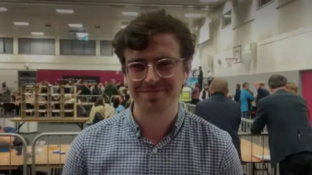 Adam Mandeville wearing a check blue and white shirt